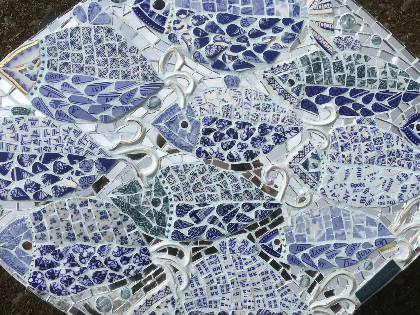 a mosaic of fish with the tiles cut out of blue and white china