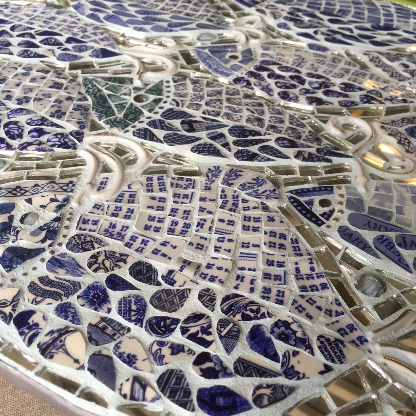detail image of a mosaic of fish with the tiles cut out of blue and white china