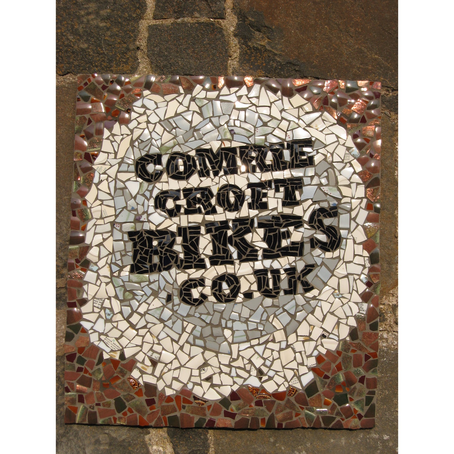 sign in mosaic saying Comrie Croft Bikes dot co dot UK. The design includes a bike wheel
