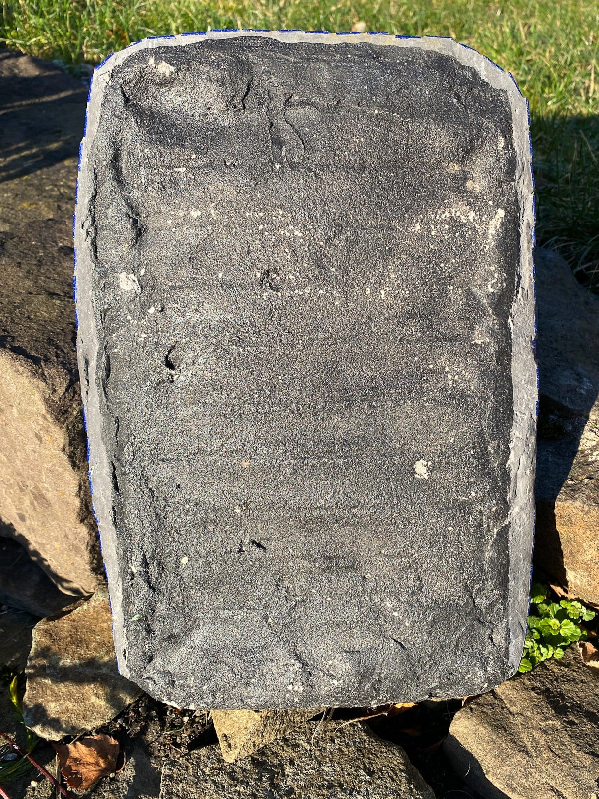 grey reverse of the rectangular shrine which is on a stone step and a bit of lawn visible