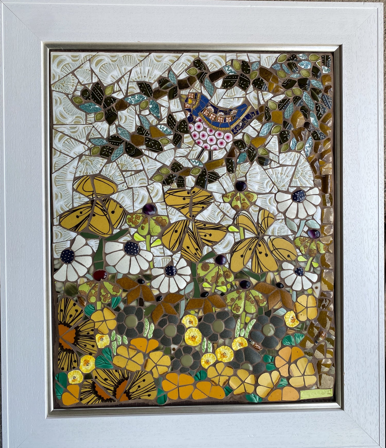 Mosaic artwork with mustard yellow flowers in a decorative frame.