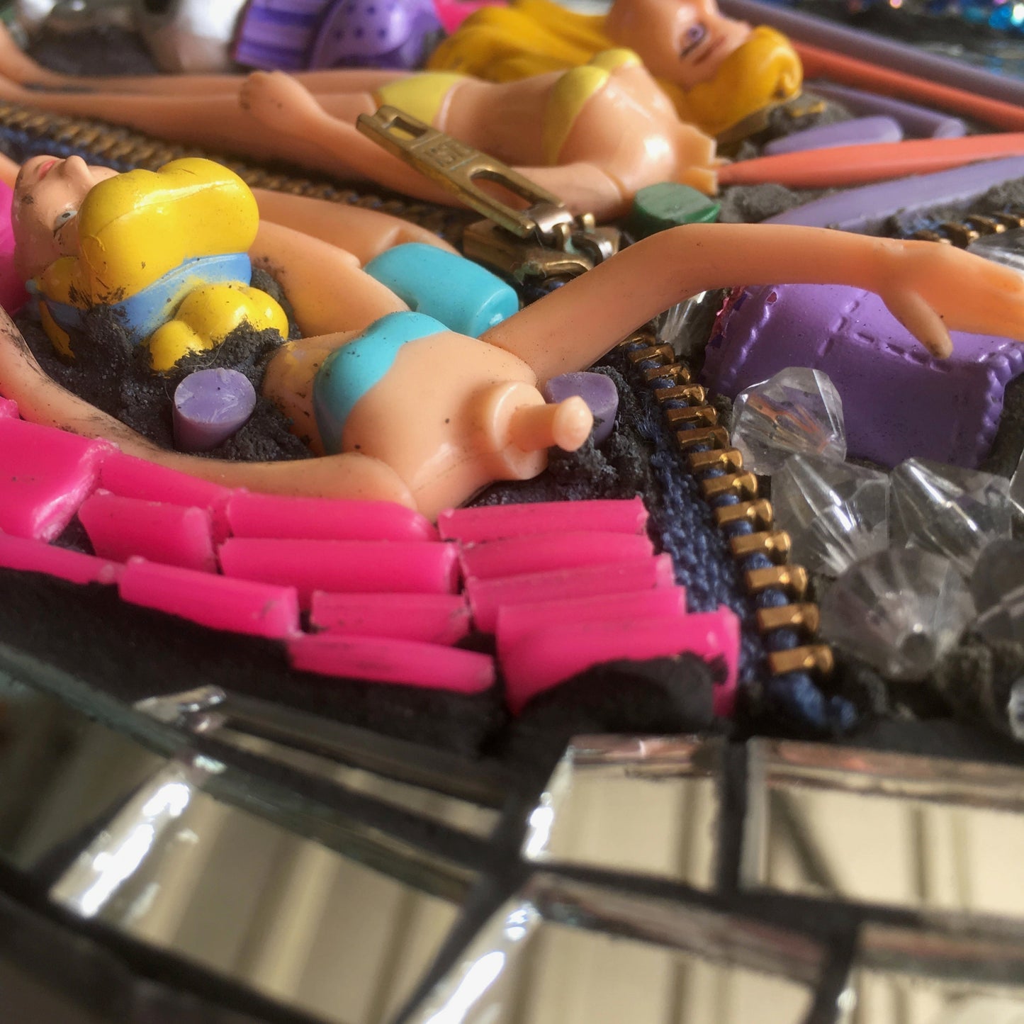 detail image showing two headless plastic dolls, one with her arm up, and part of a zip