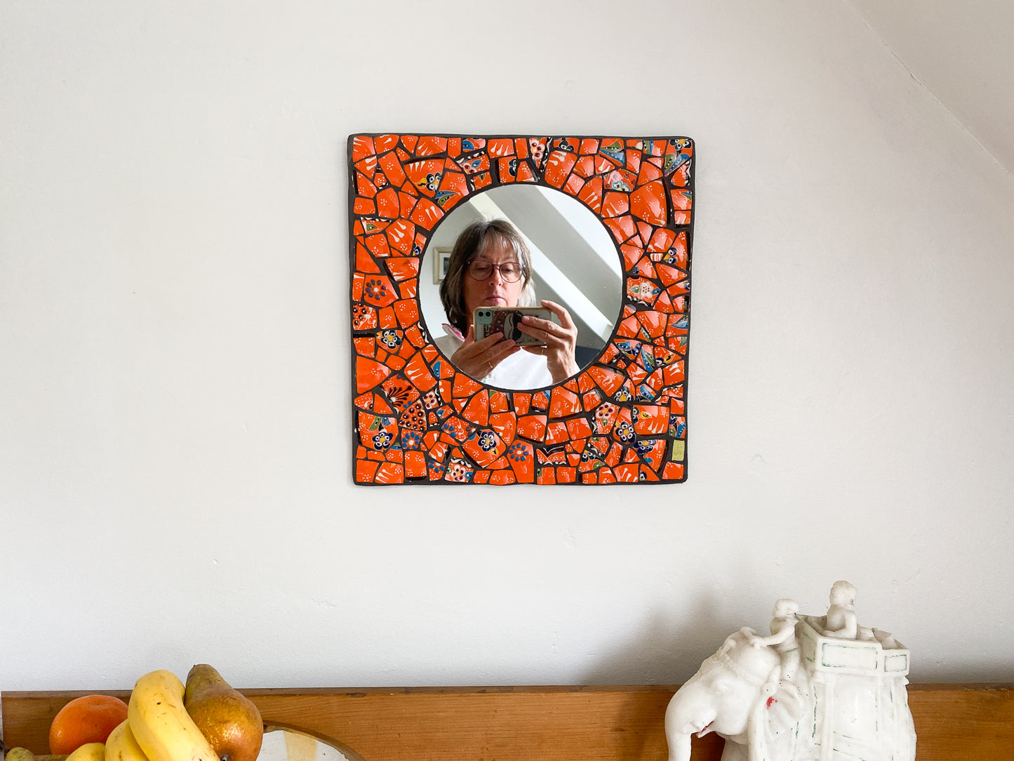 Bright orange mosaic mirror made from Turkish pottery. Square in shape with a circular mirror