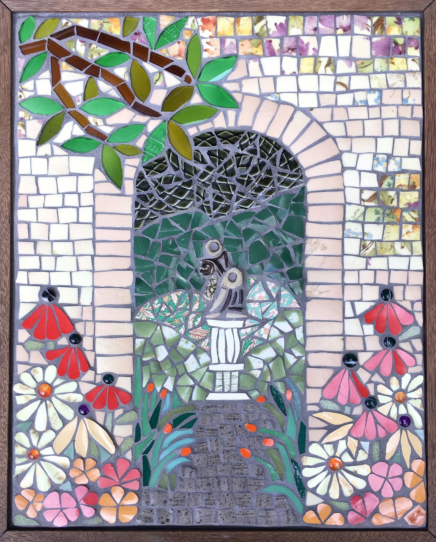 a mosaic of an archway with a branch and flowers, framed in wood