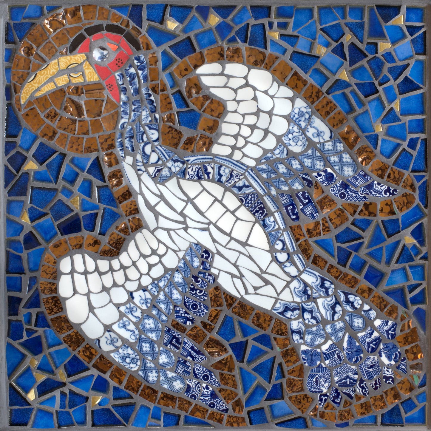 crane bird with a halo depicted in mosaic. blue tile background. The bird has a white body and the tail & wing feathers are in blue and white traditional china
