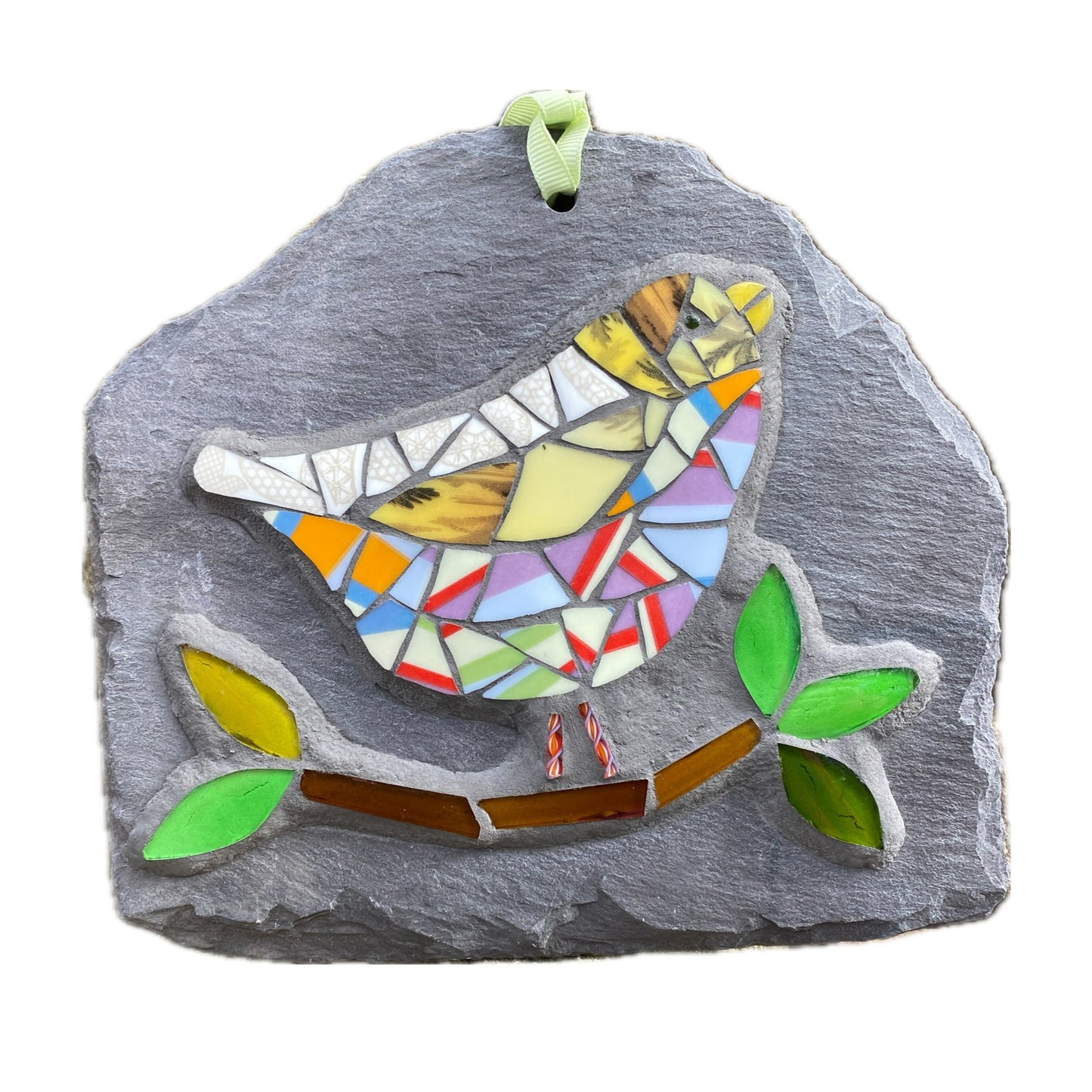 a colourful mosaic bird with lots of stripy tesserae with a branch and leaves in glass on a grey slate. photographed on a white background