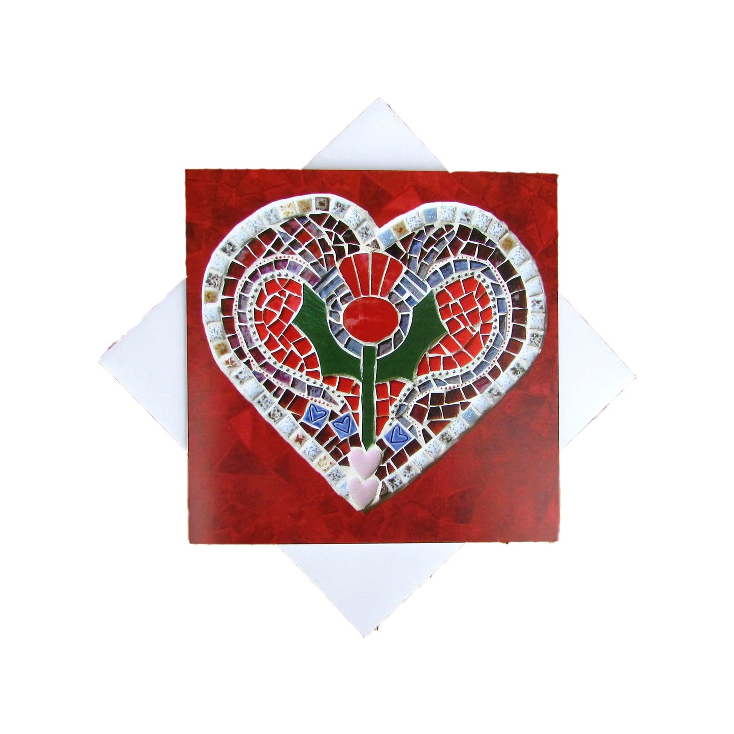 A square card with a thistle on a heart shape, in a mosaic pattern, with a red background. It is photographed with an envelope underneath, on a white background.