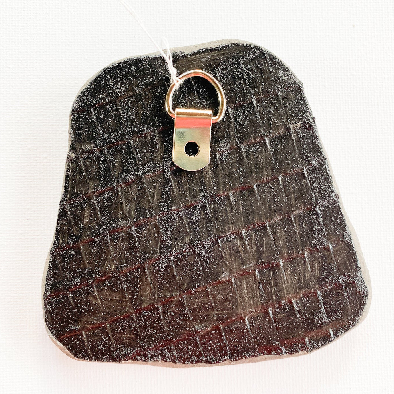 Textured reverse side of mosaic with d-ring on a white background