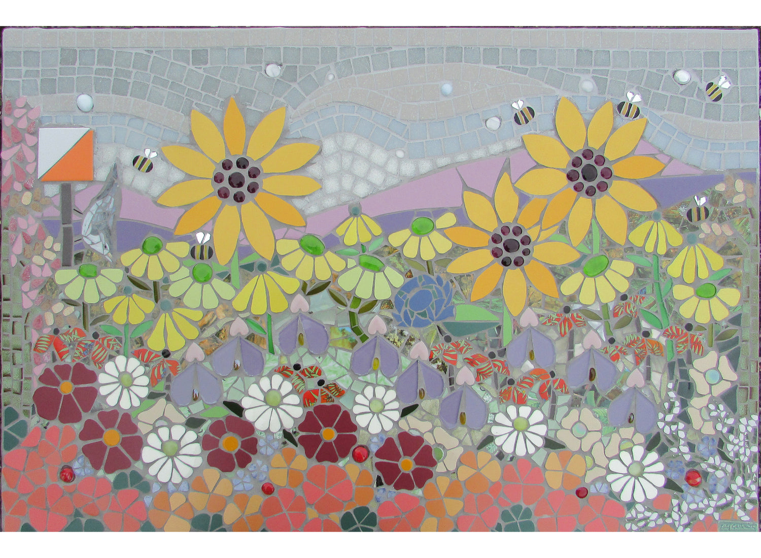 large panel of flower garden in mosaic with sunflowers and daisies. There is an orienteering flag, a scottish thistle and a nuthatch