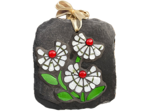 three white daisy flowers, with a green leafy detail, red glass nuggets and bright green leaves in mosaic on slate against a white background