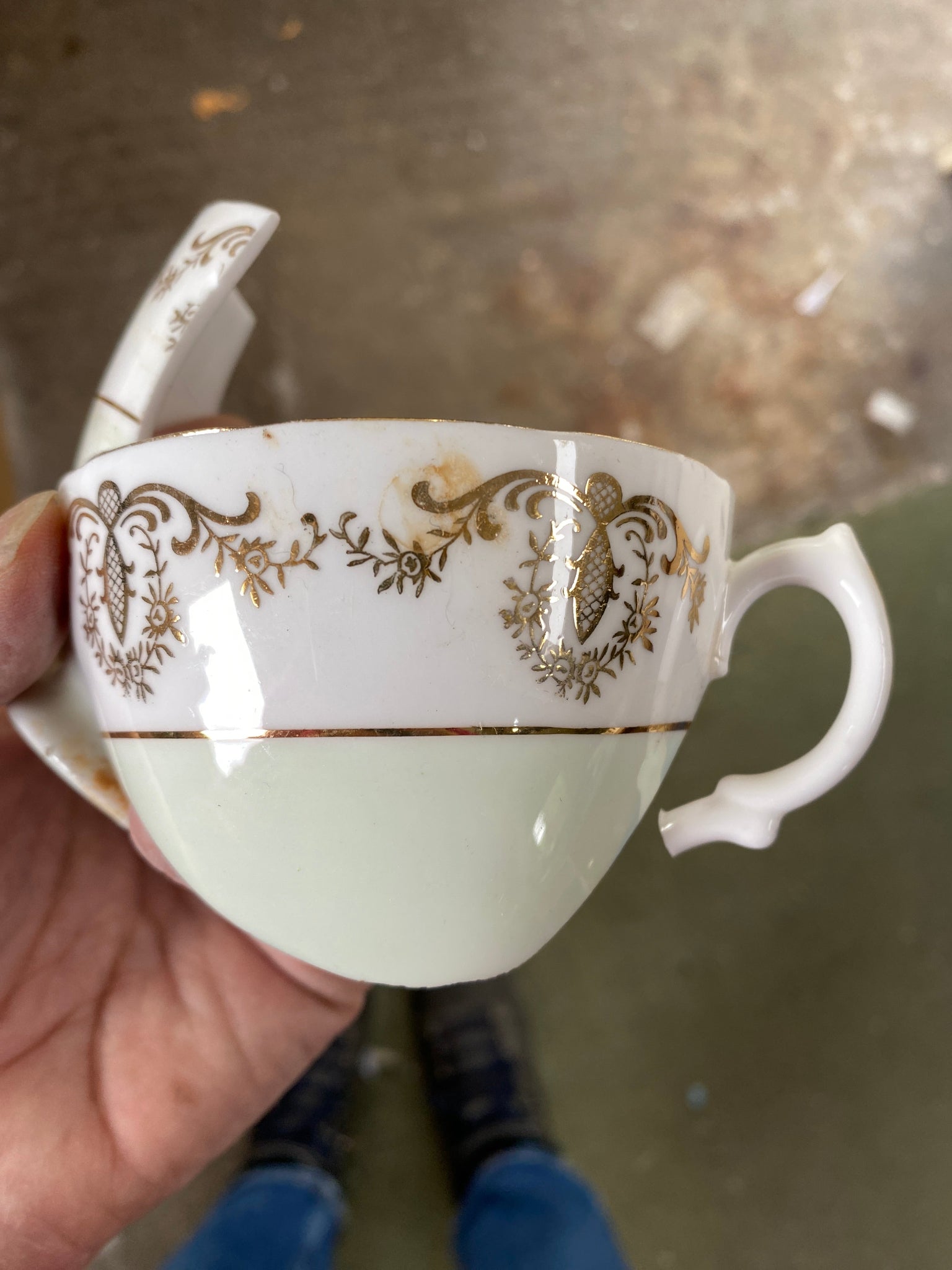 Decorative ceramic cup with floral patterns held by a hand against a blurred background