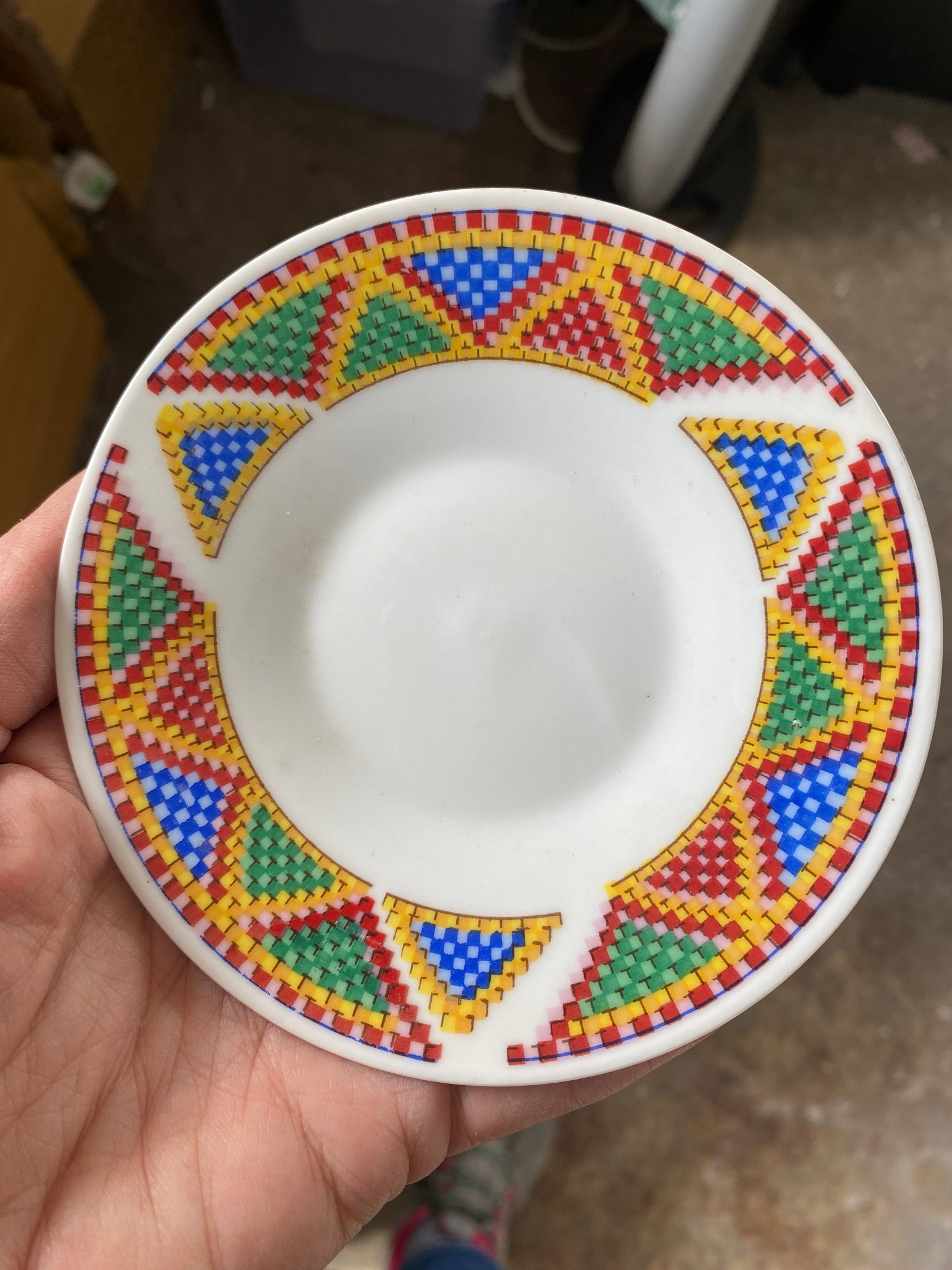 Decorative plate with colorful geometric pattern held by a hand