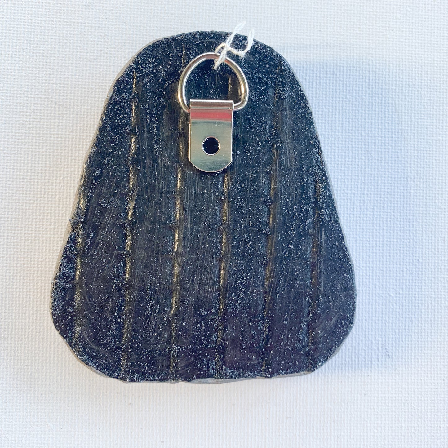 Black reverse side of a mosaic with a metal D-ring on a white background