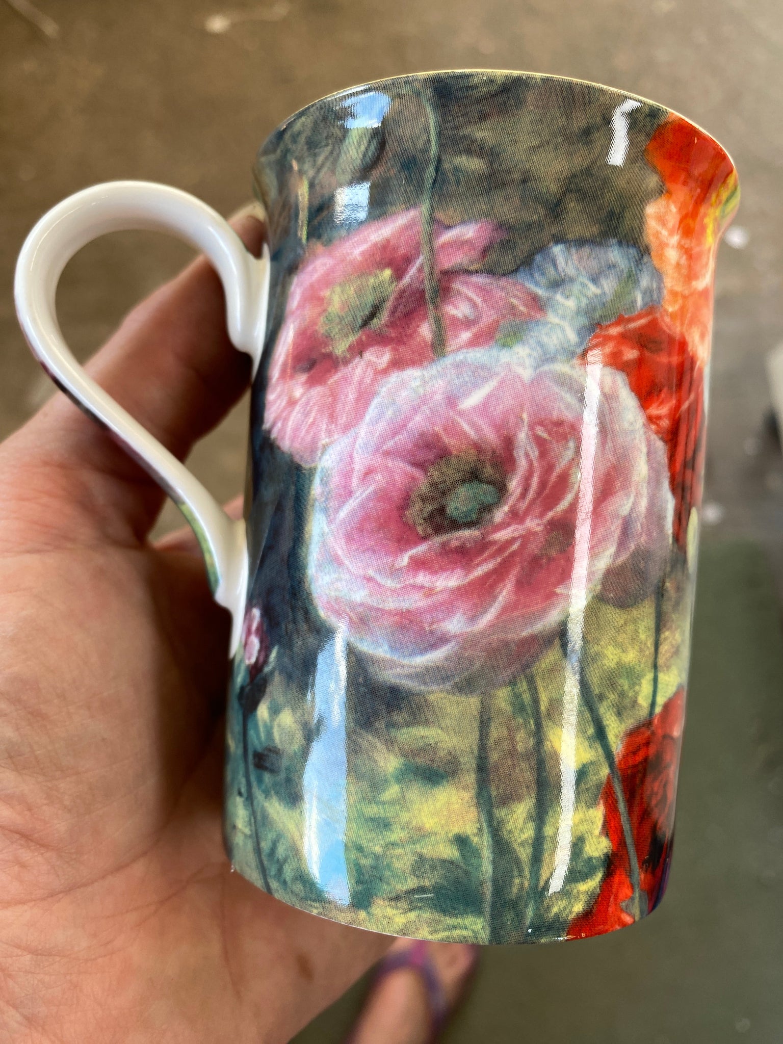 Mug with floral design held by a hand on a blurred background