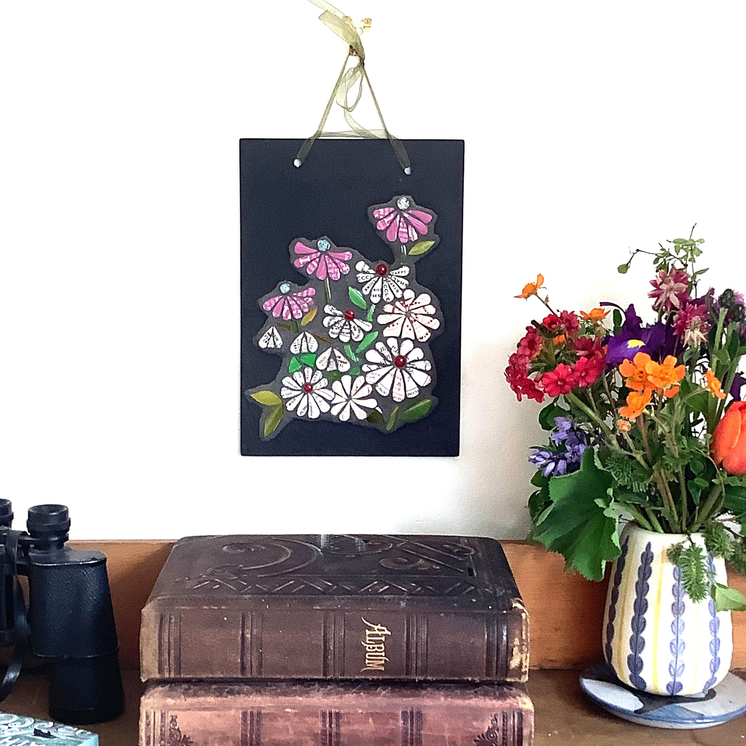 floral msoaic panel on slate, on display by a bunch of flowers and books