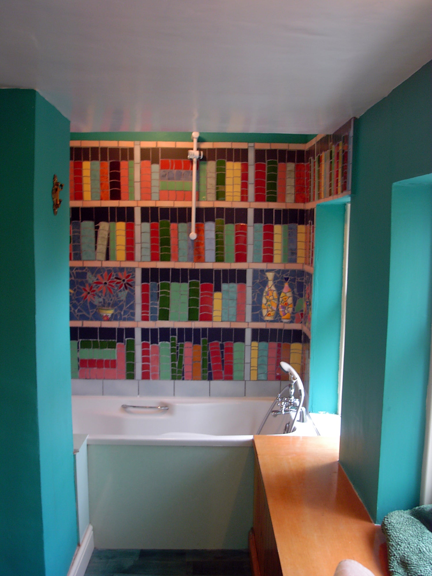 bathroom splashback mosaic depicting a shelves of a library with books and other items on them