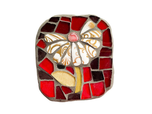 Small mosaic of white and gold petaled flower with red glass background, photographed on white