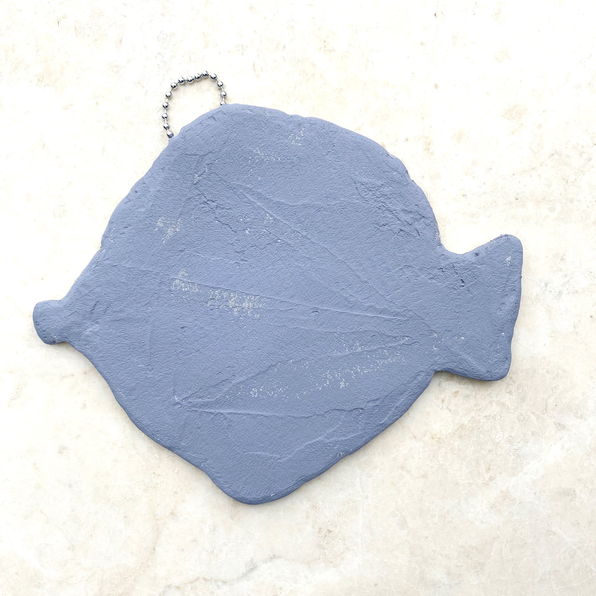 A mosaic fish made from a handmade structure.  Photographed showing the reverse of the fish, with grey paint