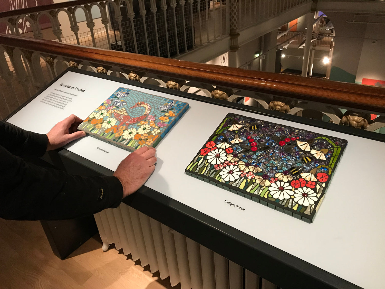 two mosaics on display. the left one is depicting a goose in a garden, and the right one shows dragonflies in a garden against a night sky