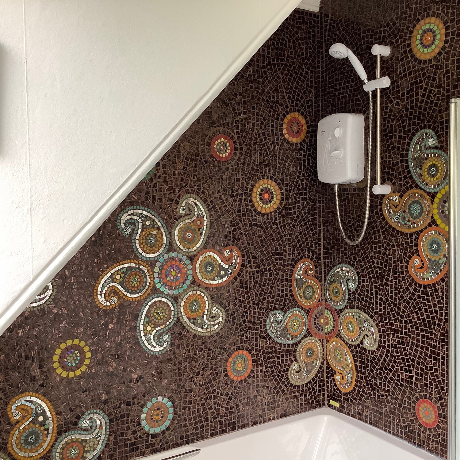 tiled backsplash in a shower over bath with mandalas with paisley shapes made in cut glass bathroom tiles