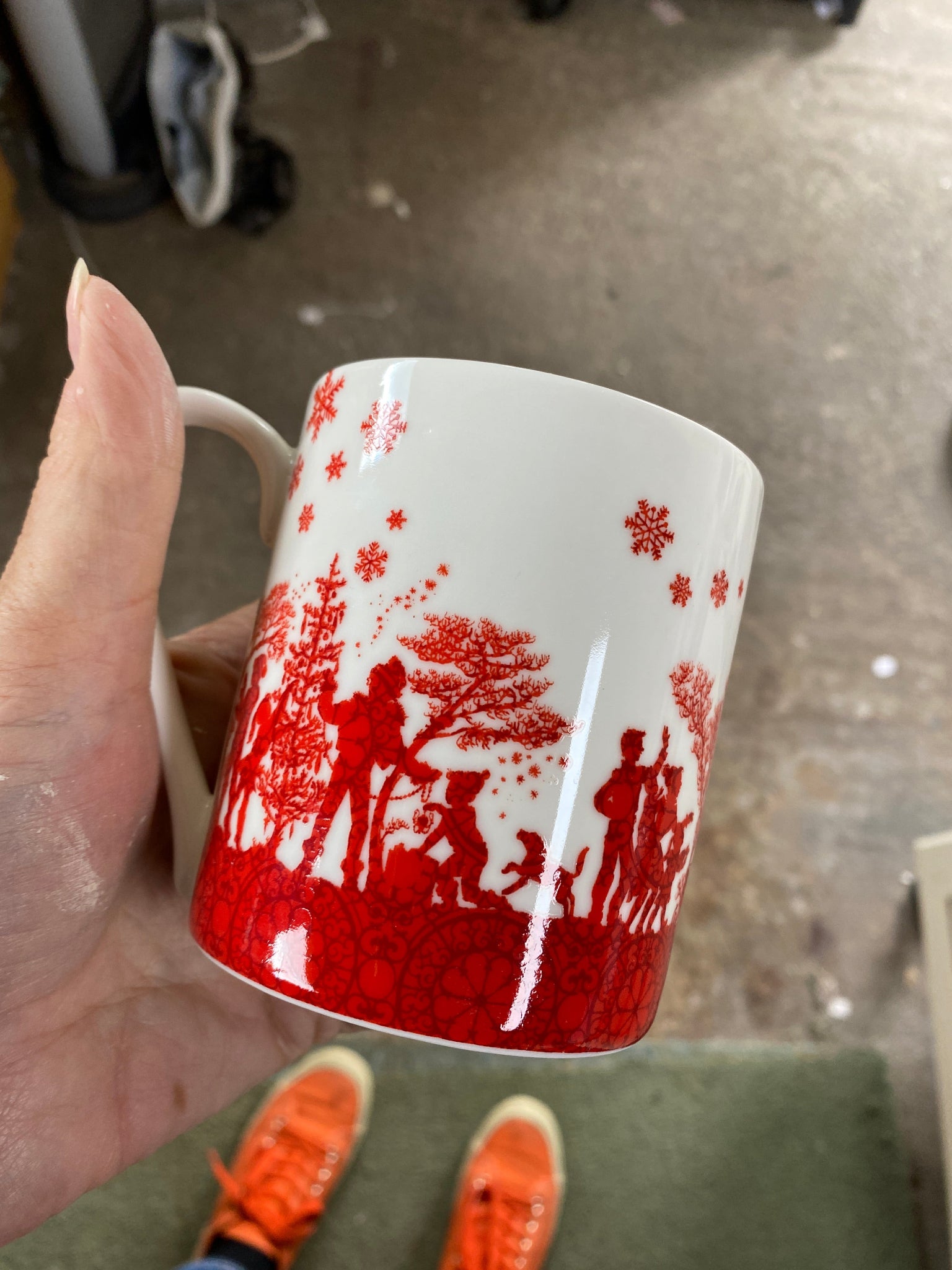 Red and white patterned mug held by a hand on a blurred background