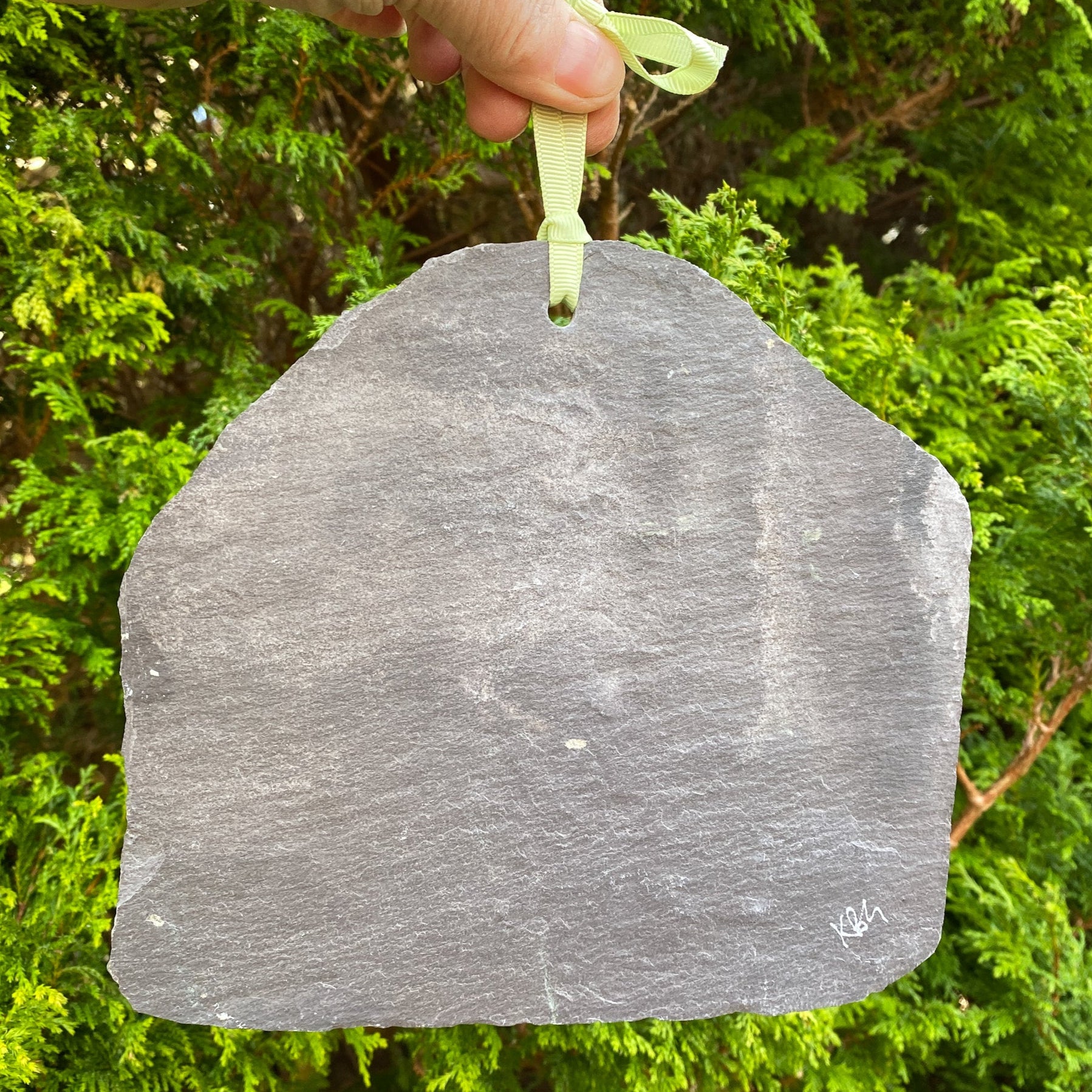 reverse side of a slate showing signature, hole for hanging and ribbon