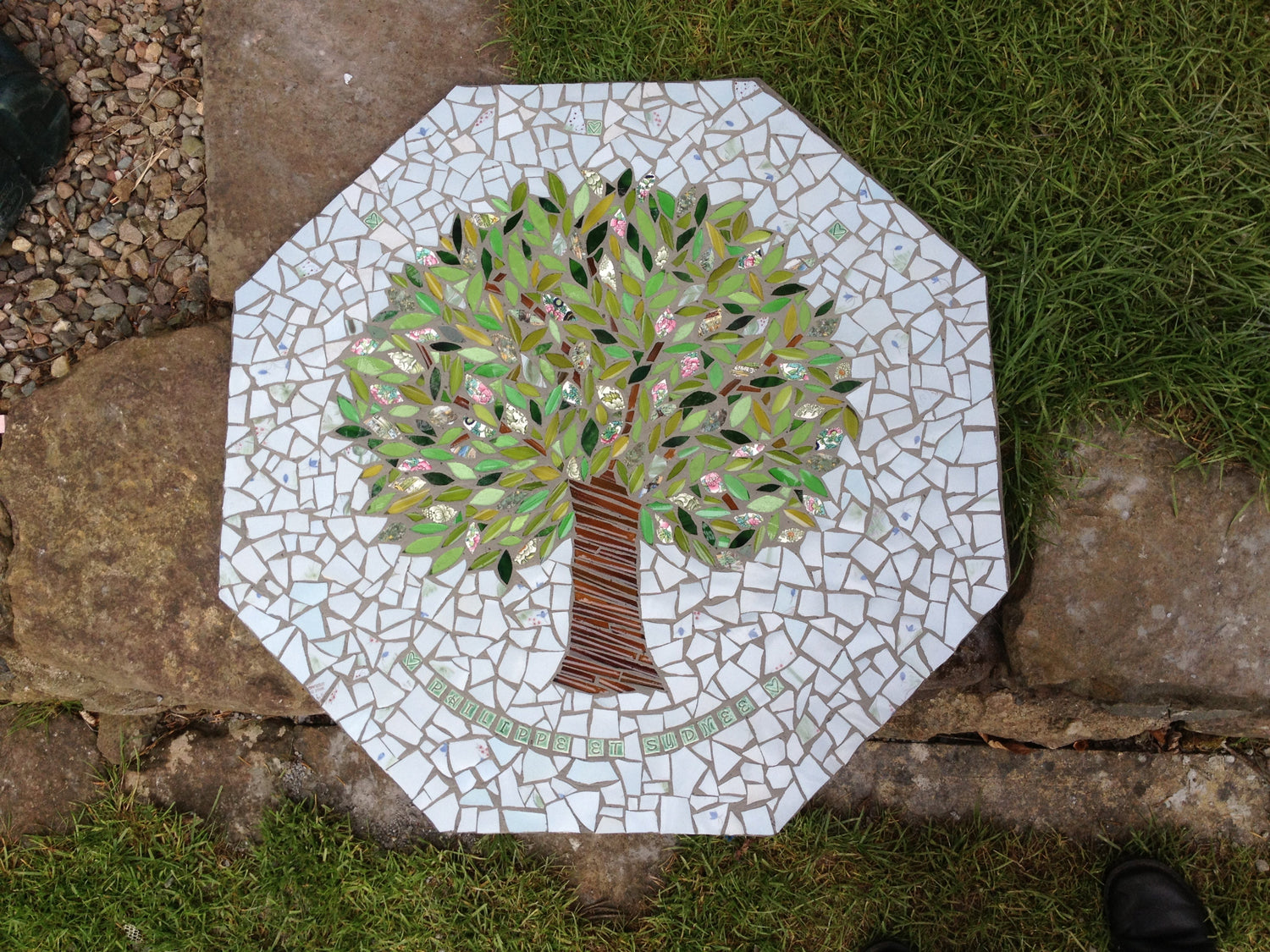 a tree made of glass, with a pale blue background, and the names of couple, a hexagon table top in mosaic