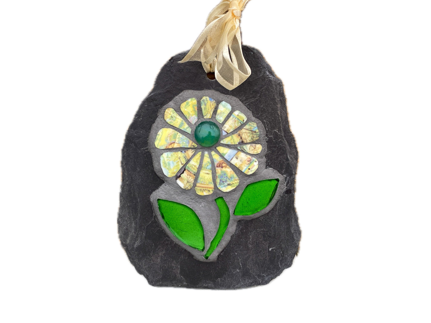 Mosaic flower with yellow patterned petals, and bright green leaves, on slate. Shown on a white background
