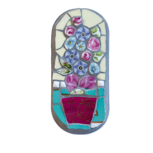 Mosaic art piece in an anchovy tin with floral design on a  white background