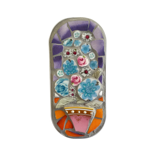 Mosaic art piece in an anchovy tin with floral design on a  white background