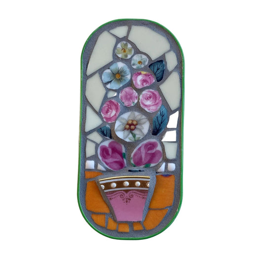Mosaic art piece in an anchovy tin with floral design on a  white background