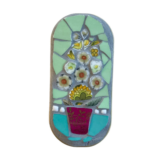 Mosaic art piece in an anchovy tin with floral design on a  white background