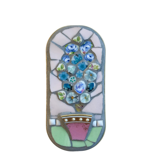 Mosaic art piece in an anchovy tin with floral design on a  white background