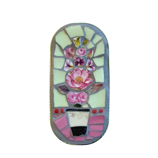 Mosaic art piece in an anchovy tin with floral design on a  white background