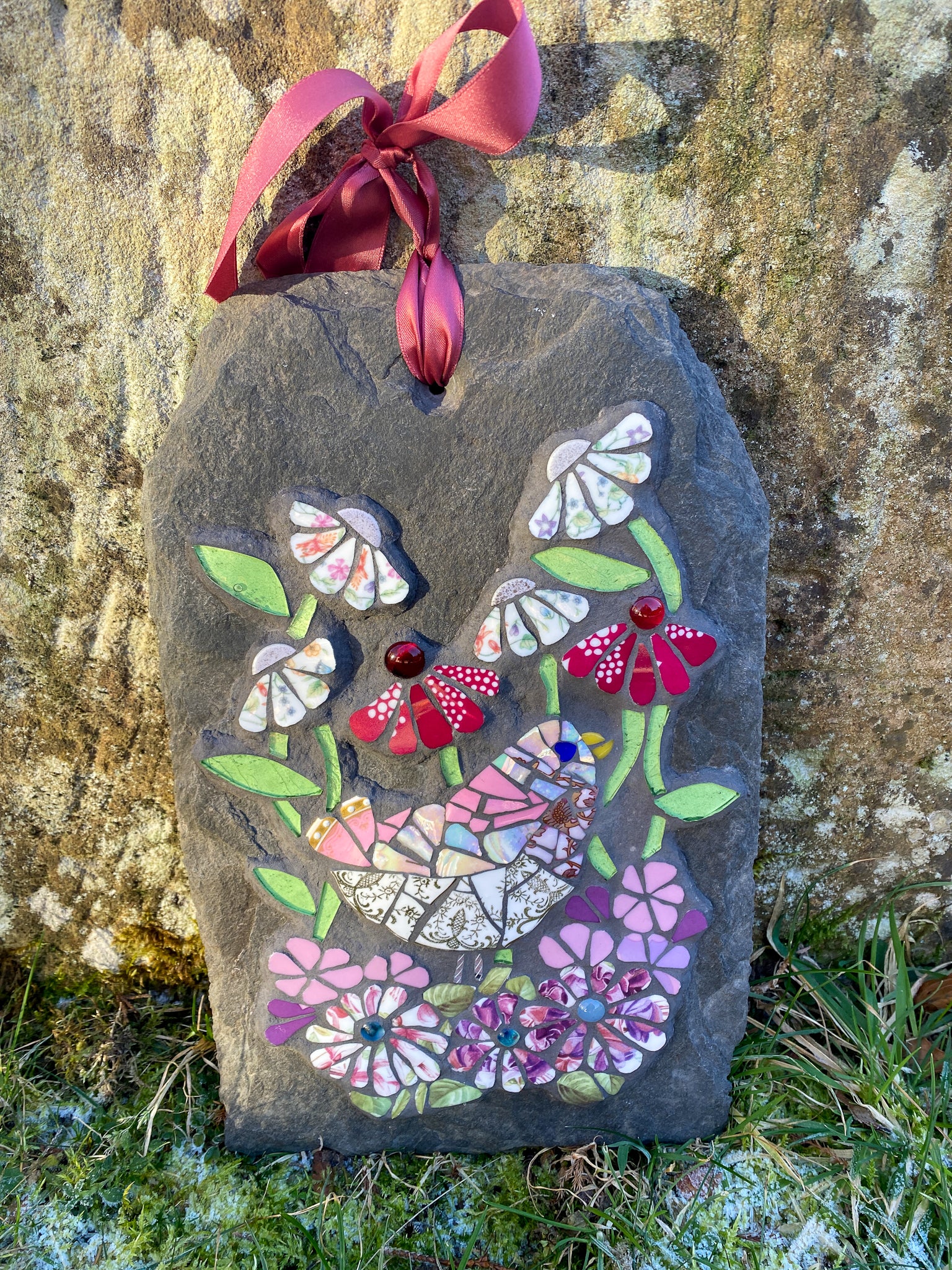 mosaic on slate of a pink gold and white bird surrounded by mosaic flowers in pink, hot pink and chintz tones.  leaves in pale green glass