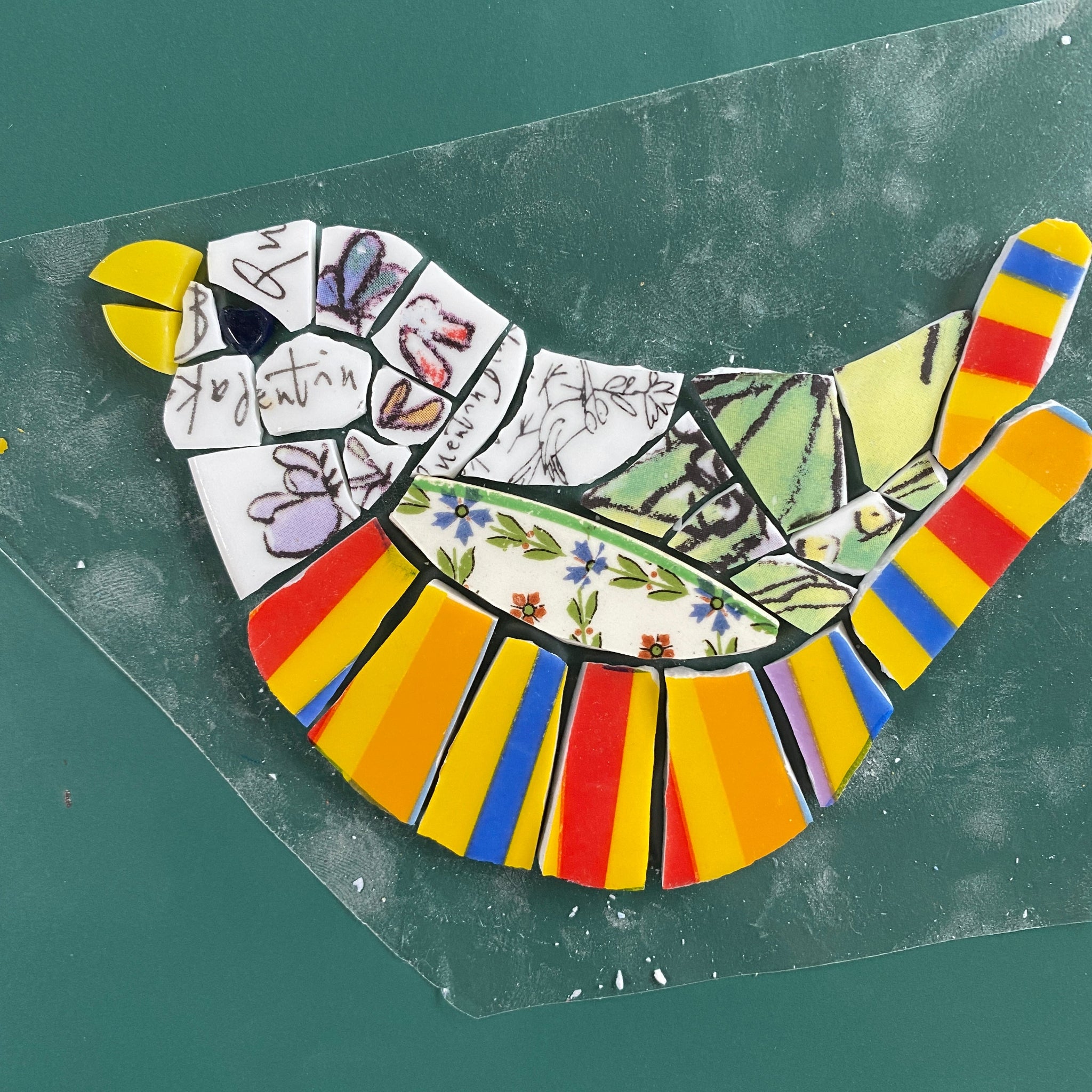 colourful bird mosaic from various china laid out on plastic