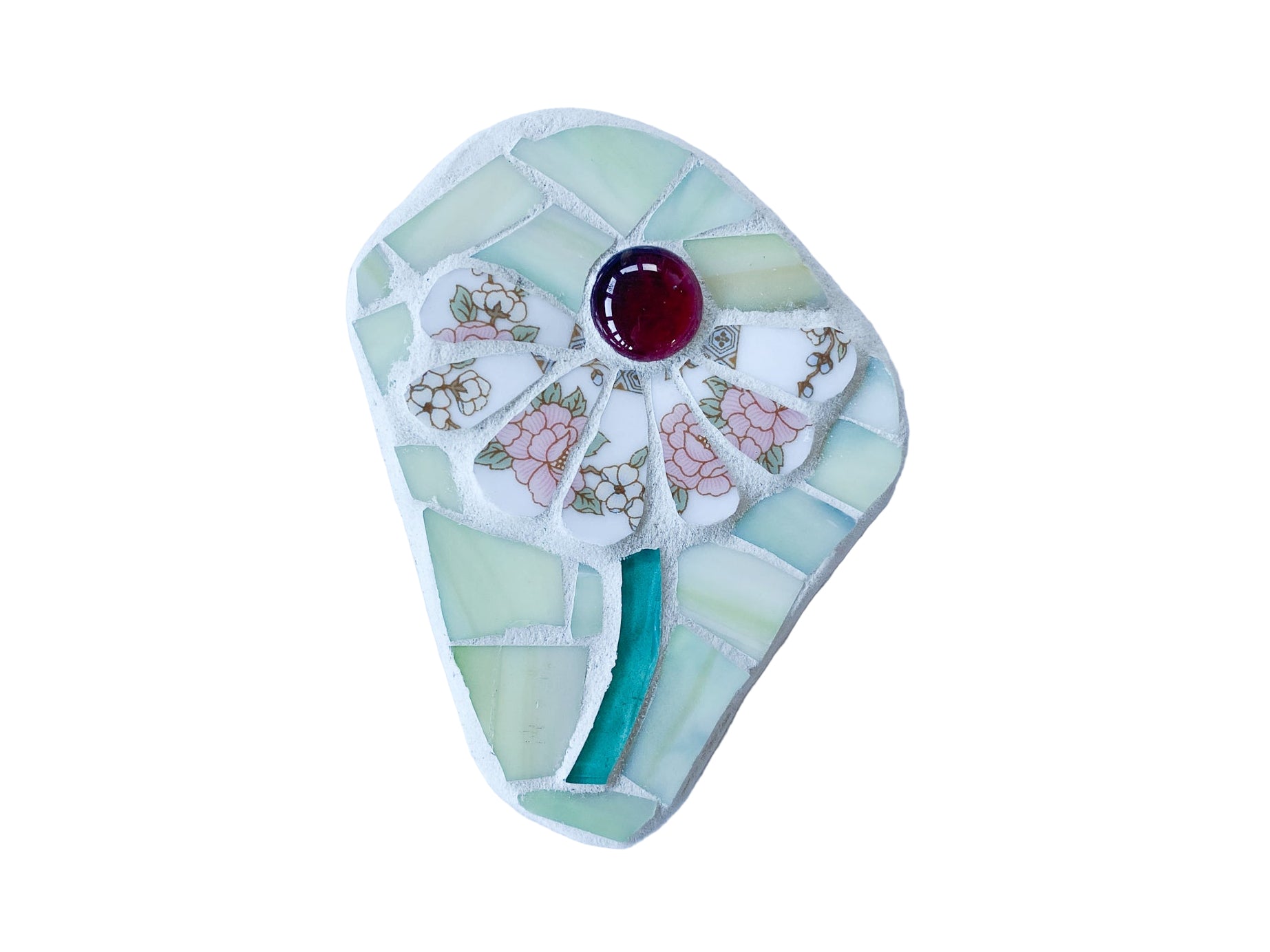 Decorative mosaic with floral design and red glass nugget on a photographed on a white background