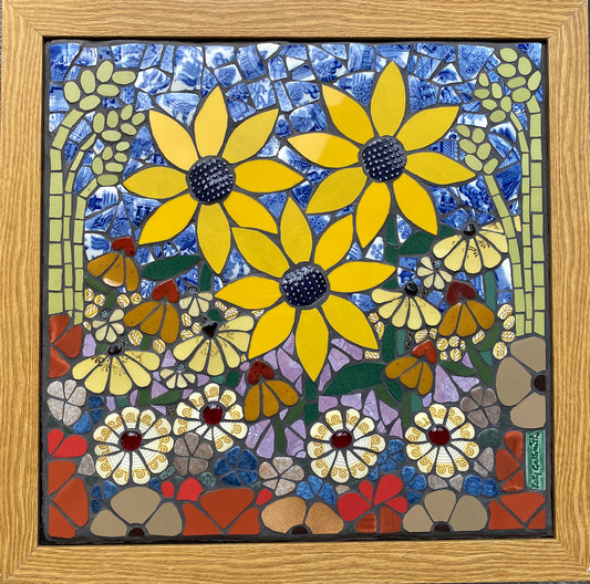Mosaic artwork with yellow sunflowers, grasses and daisiy flowers and a wooden frame