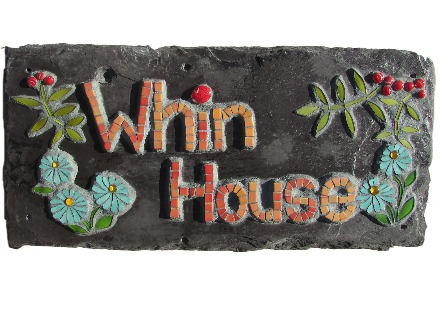 Whin house is in orange mosaic, with flowers and leaves around on a roof slate